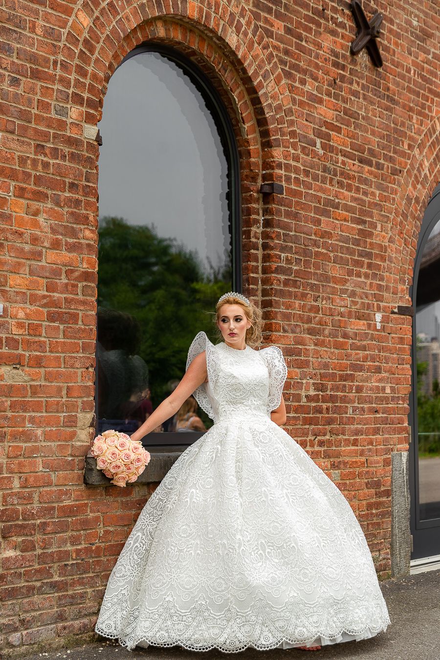 An elegant full-length wedding photo showcasing a classic white ball gown against historic architecture.