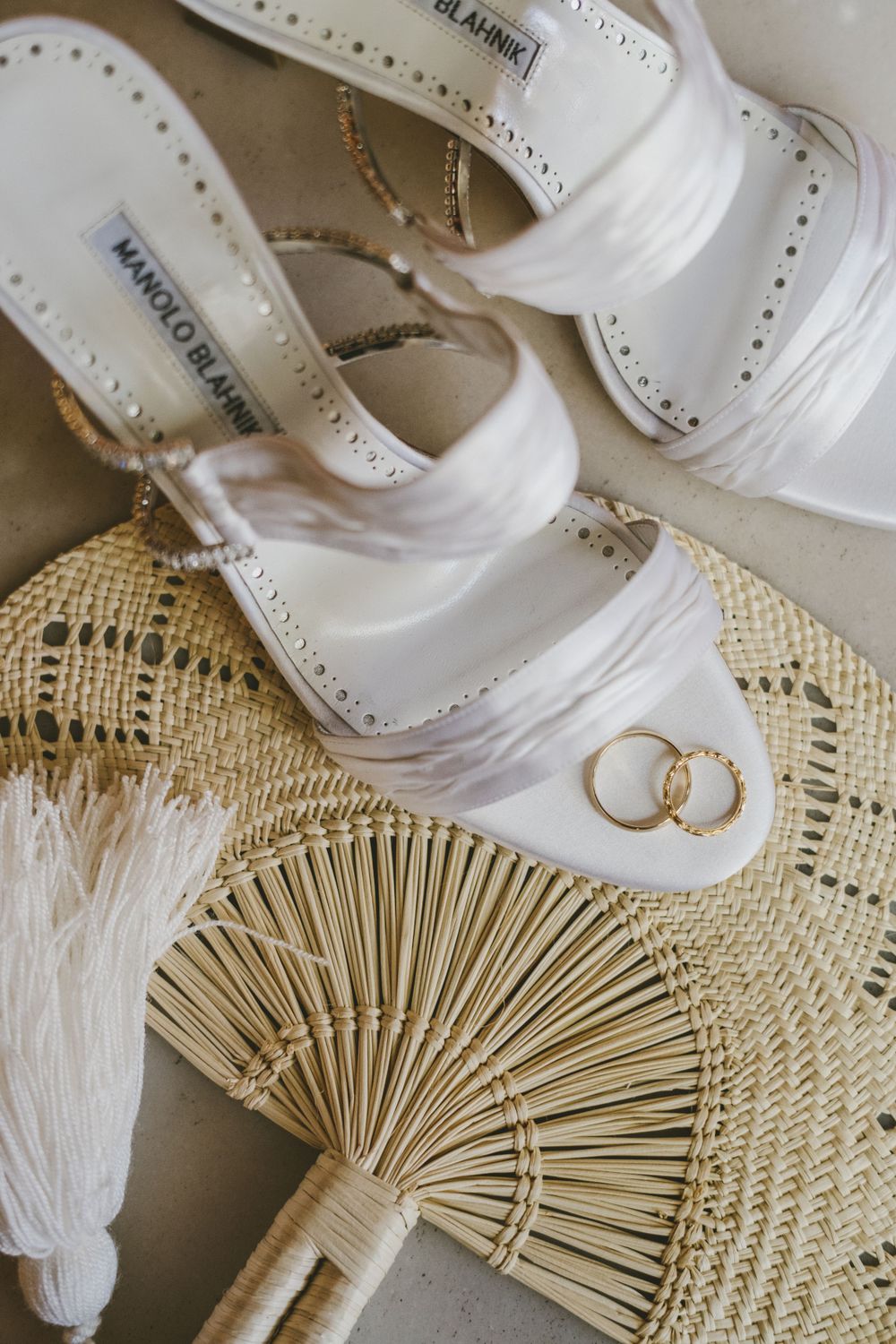 Wedding rings resting on top of the bride's heels and on a traditional handmade Colombian fan.