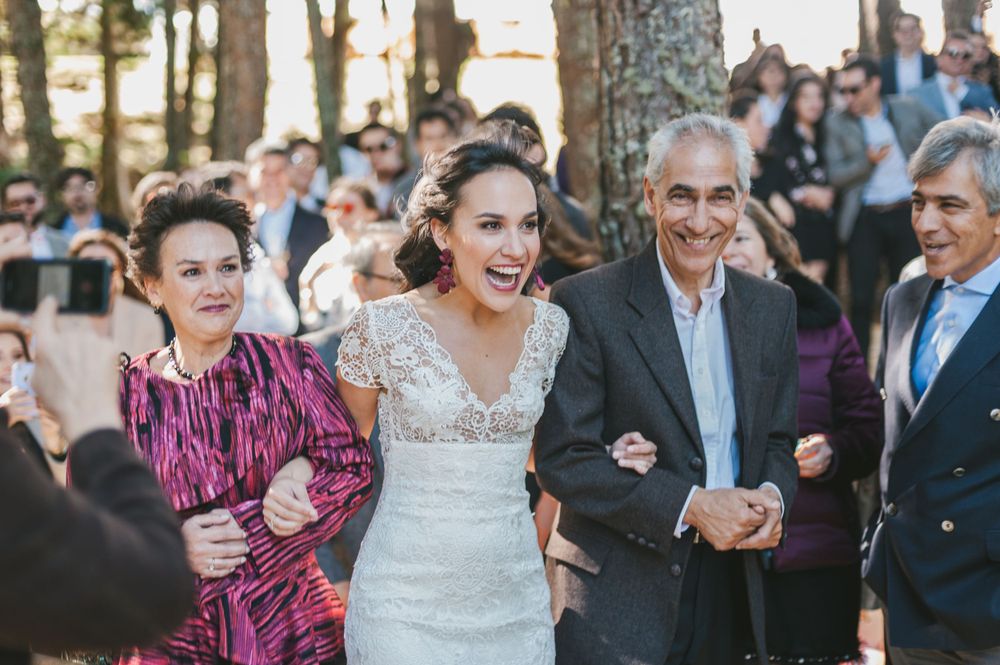 Bride ecstatically smiles as she arrives at her wedding ceremony escorted by her parents.