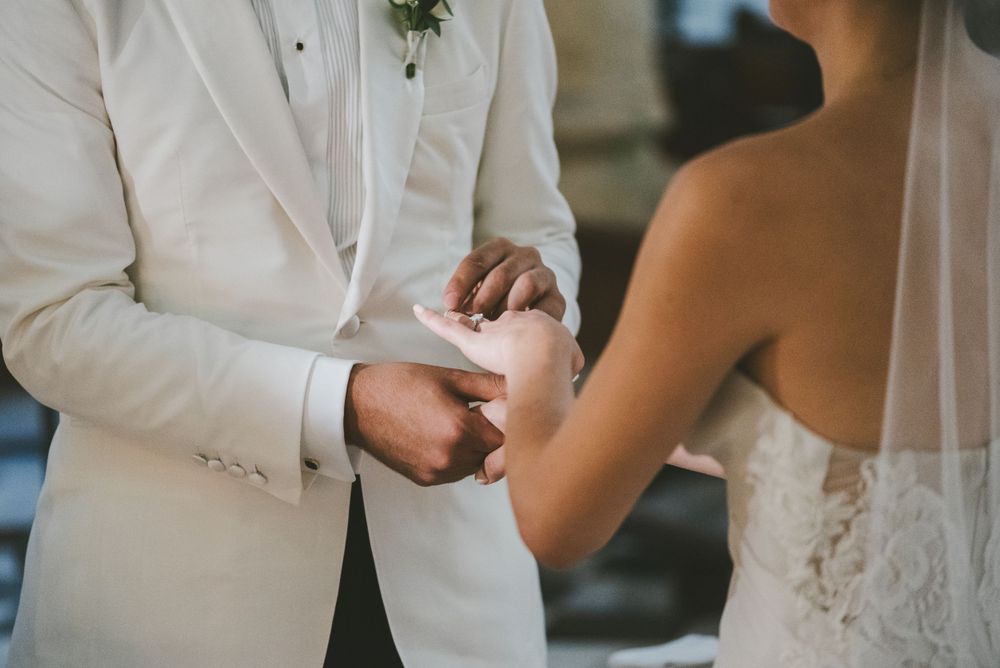 Groom placing wedding ring in his wife's hand during ceremony in Cartagena.