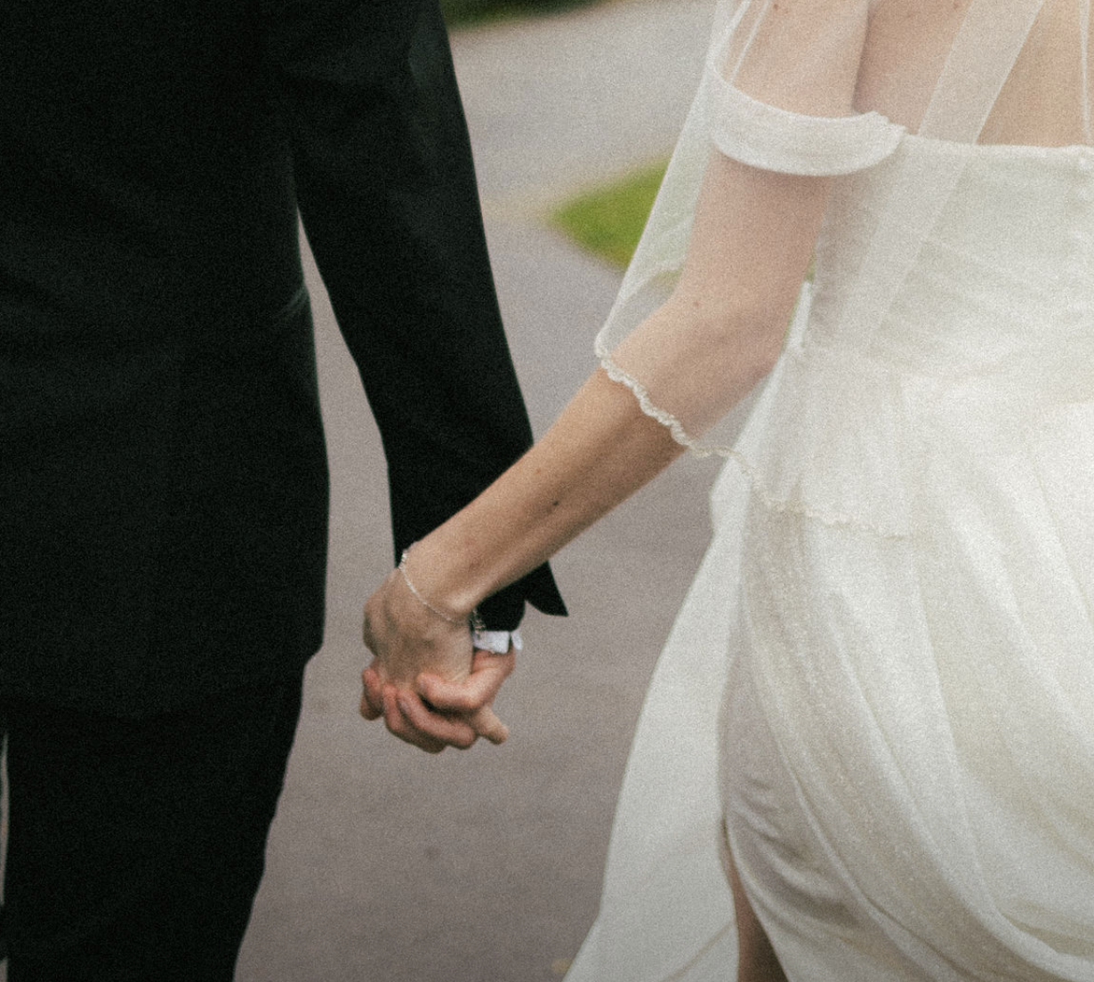 Close-up detail of wedding attire showing formal black suit and white dress.