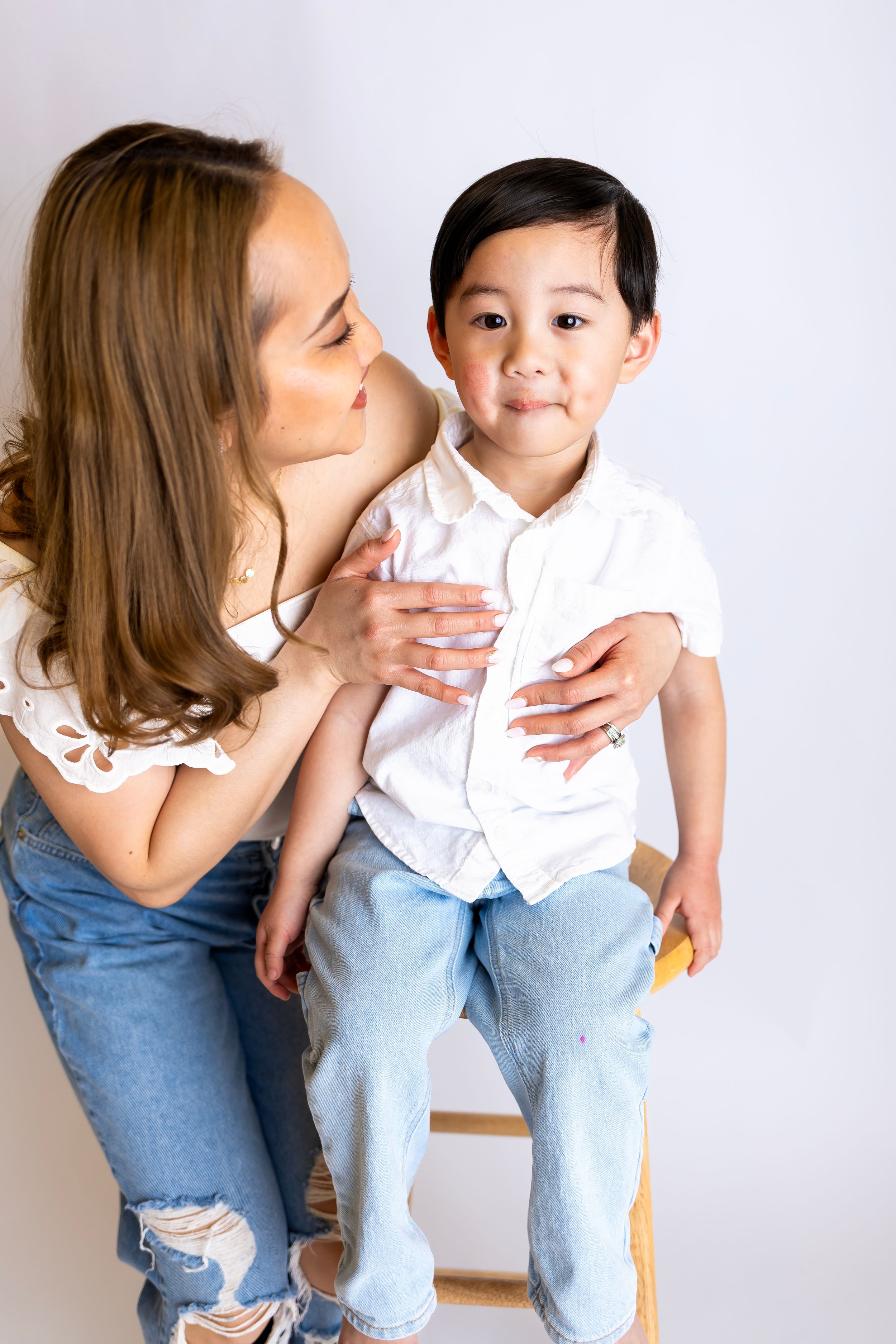 A tender moment shared between parent and child wearing casual clothing against a white background.