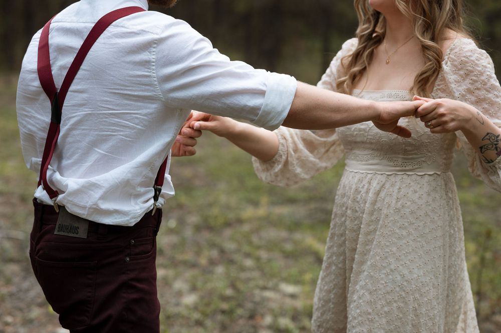 A dancing couple in wedding attire with red suspenders and lace dress details.