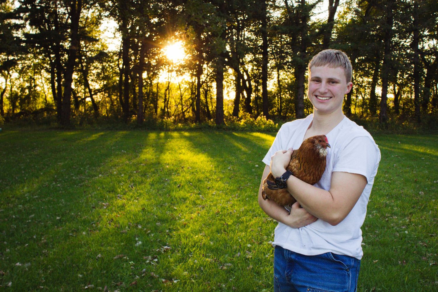 A sunset portrait in a wooded area holding a small brown puppy.
