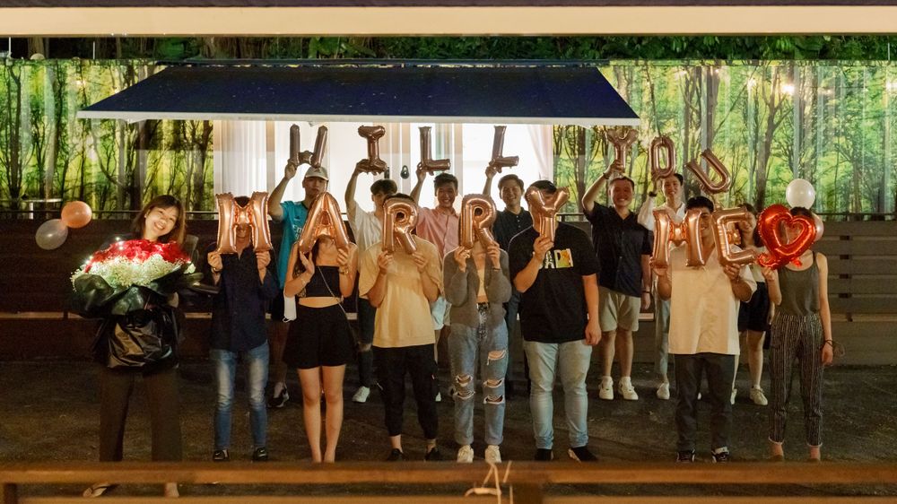 A group of people stand together under a dark canopy at an outdoor nighttime gathering.