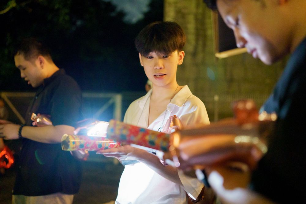 People holding glowing light toys or sparklers at night in an outdoor setting.
