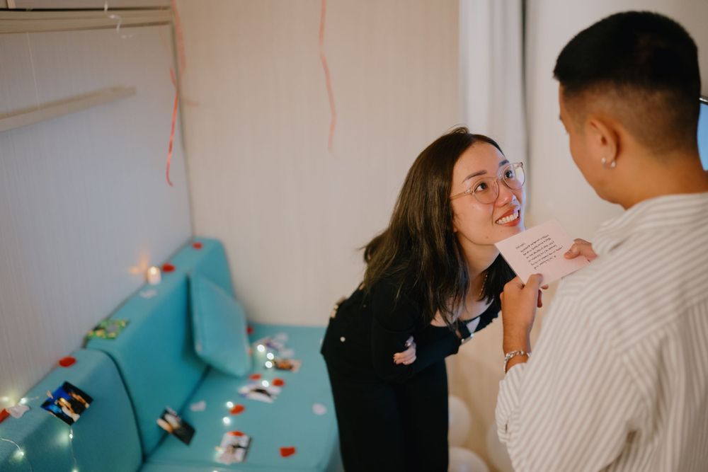 Two people share a tender moment by a wall decorated with string lights and turquoise fabric.