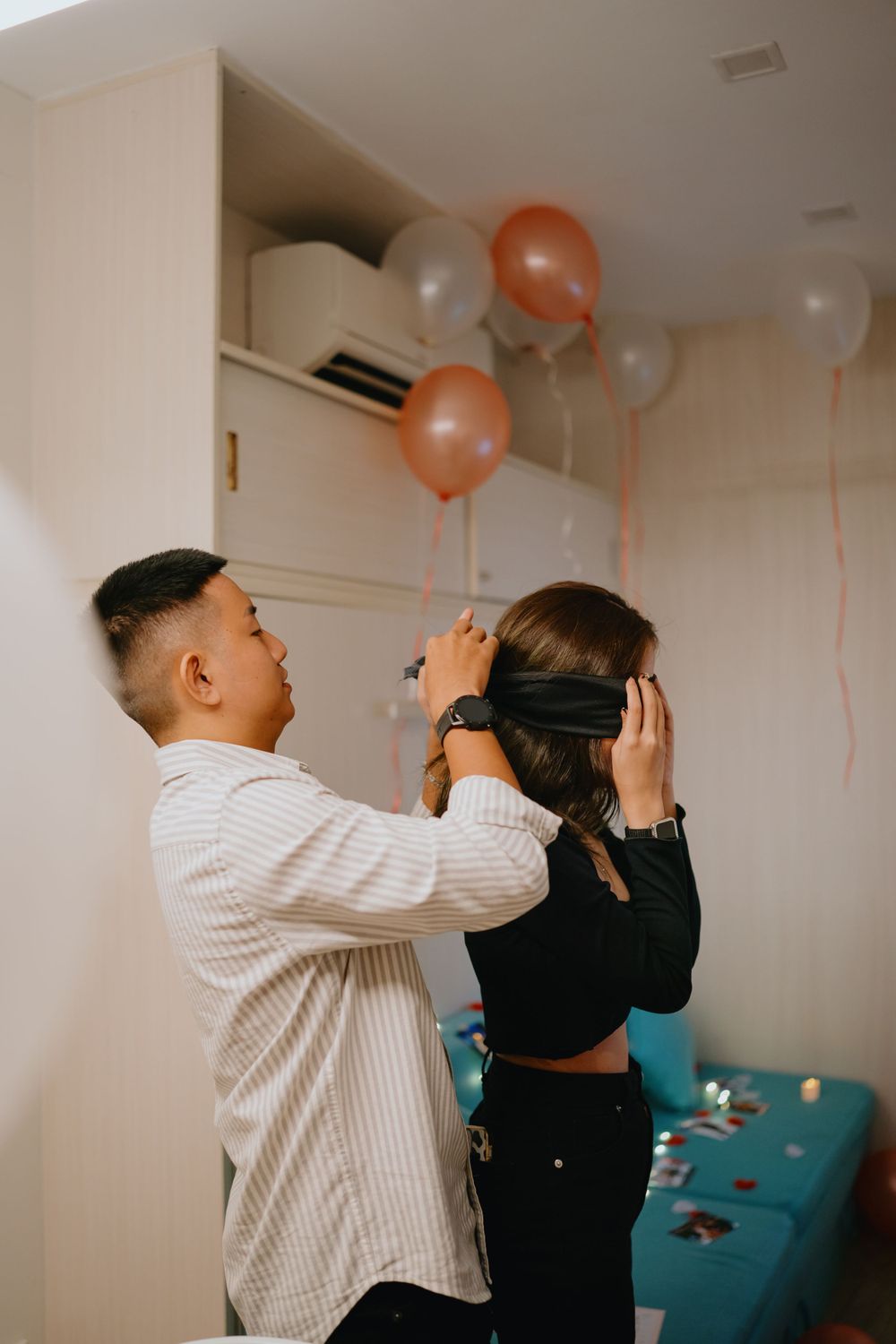 Two people in casual attire laughing and celebrating at a party with orange and white balloons in the background.