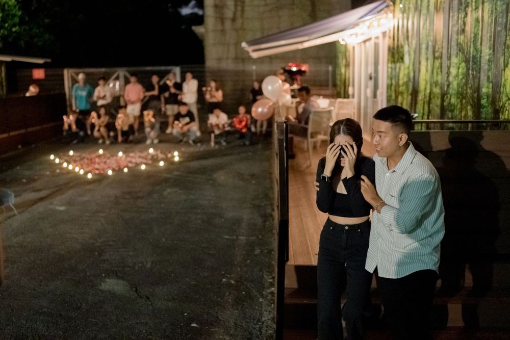 A romantic nighttime scene with string lights illuminating an outdoor restaurant patio with people gathered in the background.