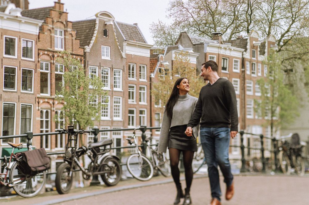 A couple sharing an intimate moment along Amsterdam's iconic canal houses.