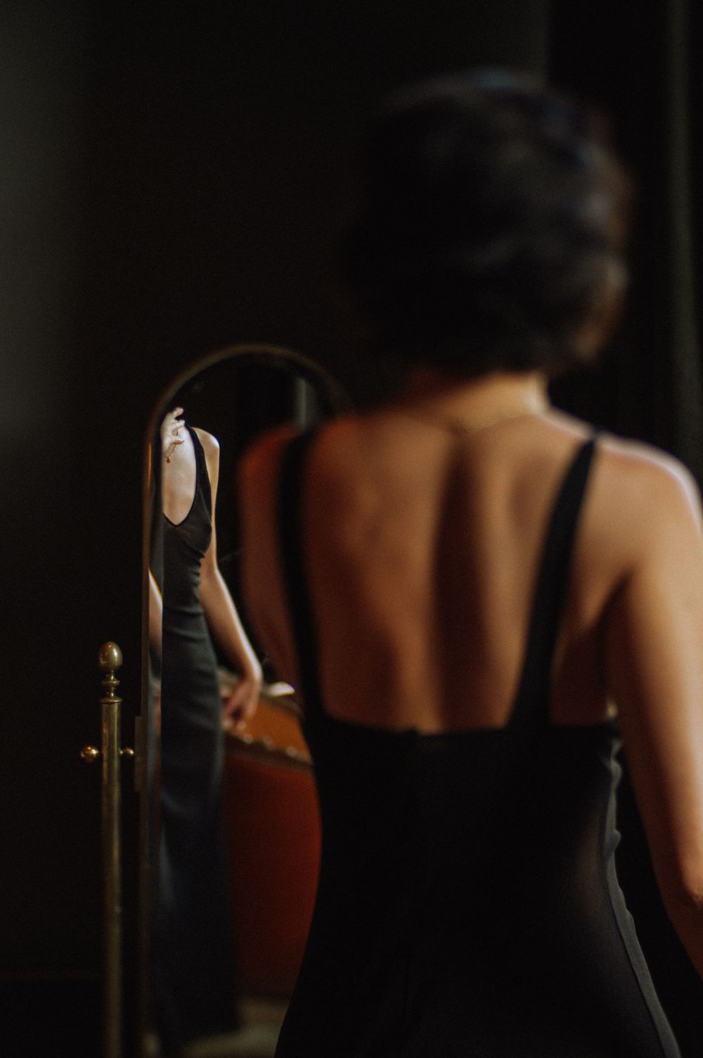 Dramatic low-key photograph showing silhouette against dark background with door handle visible.