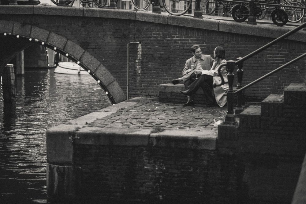 A couple sitting on canal steps in black and white, enjoying a quiet moment.