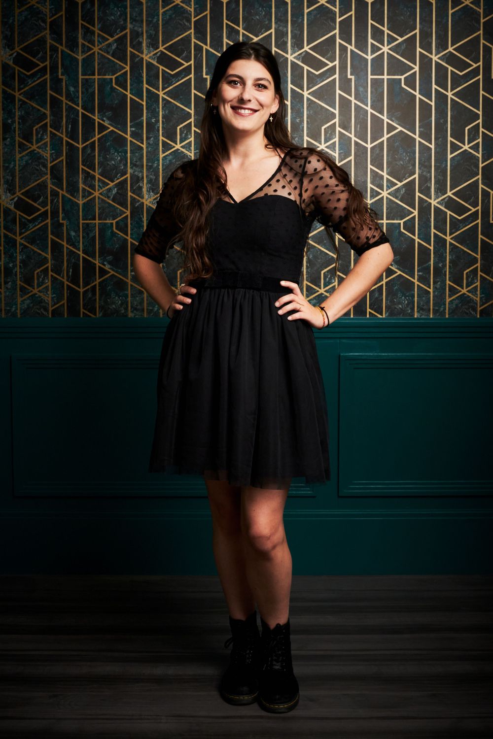 Black lace and tulle dress styled with ankle boots against geometric patterned wall and dark green wainscoting.