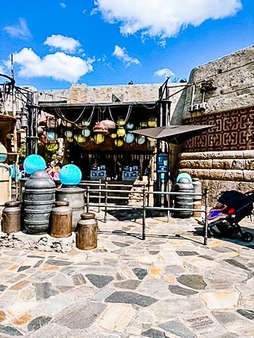 Stone courtyard entrance with barrel decorations and hanging lanterns.