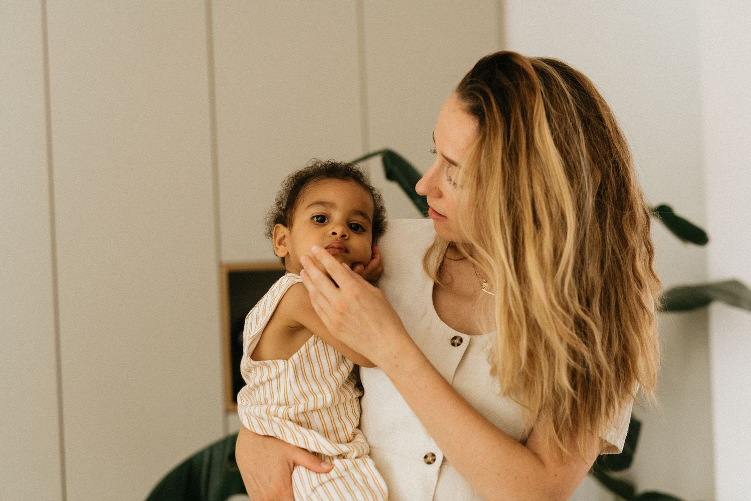 A tender moment between parent and child sharing laughter in a sunlit room.