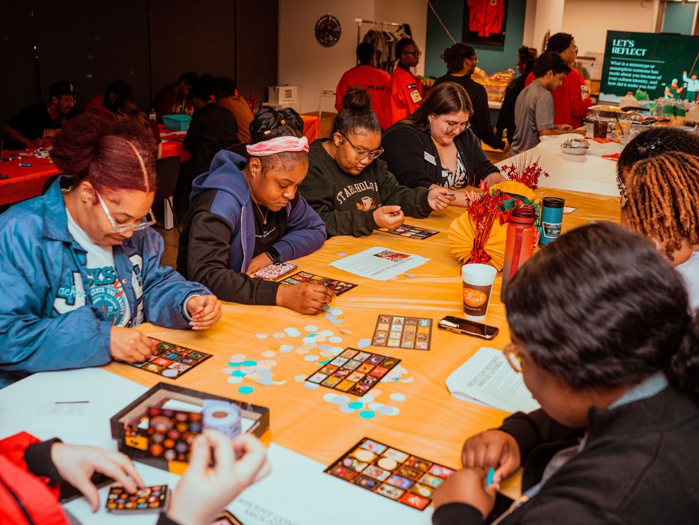 People playing board games at tables during a social gaming event in a community space.