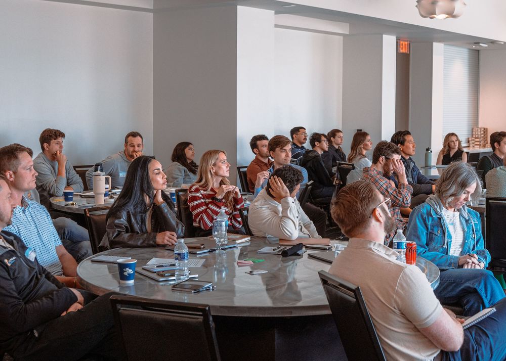 Large group of attendees seated in rows during a corporate presentation in a modern office space.