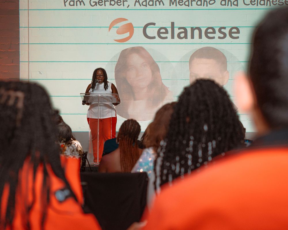 A line of athletes in orange uniforms stand together during a sports event.
