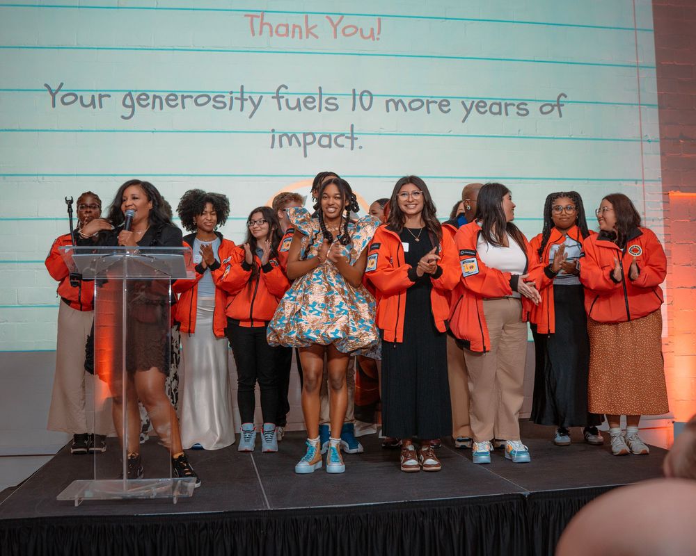 People gather at an event with presentation screens showing text about generosity and impact.