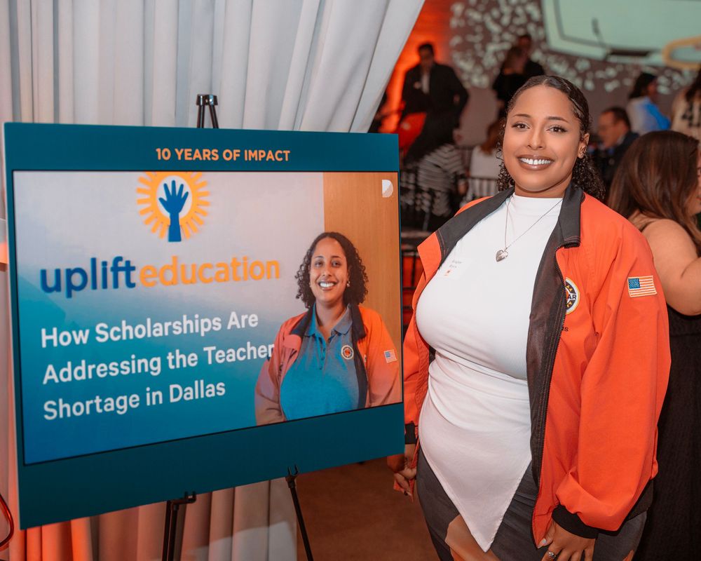 Conference attendees gather in front of education-themed banners and displays with orange and teal branding.