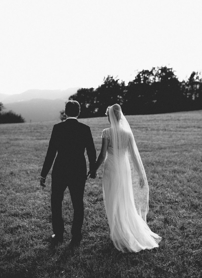 Bride and groom walking across alpine meadow during Dolomites wedding
