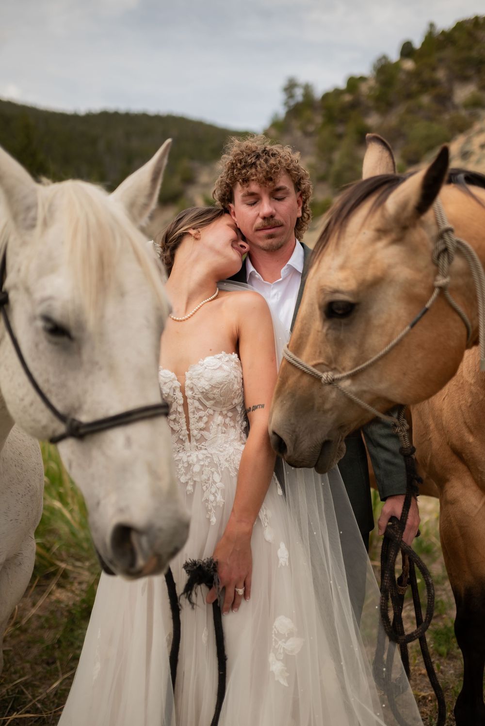 Horses nuzzle close to a couple during an intimate outdoor wedding photoshoot in nature.