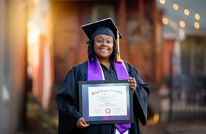 Graduates in black caps and gowns proudly display their diplomas while smiling during a graduation ceremony.