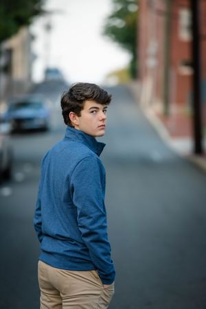 A person in a blue denim jacket and khaki pants stands on a city street in a sequence of poses.