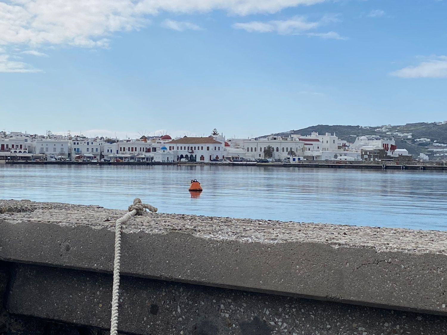 Panoramic sequence of a coastal town with white buildings nestled on hillsides overlooking a tranquil harbor at sunset.