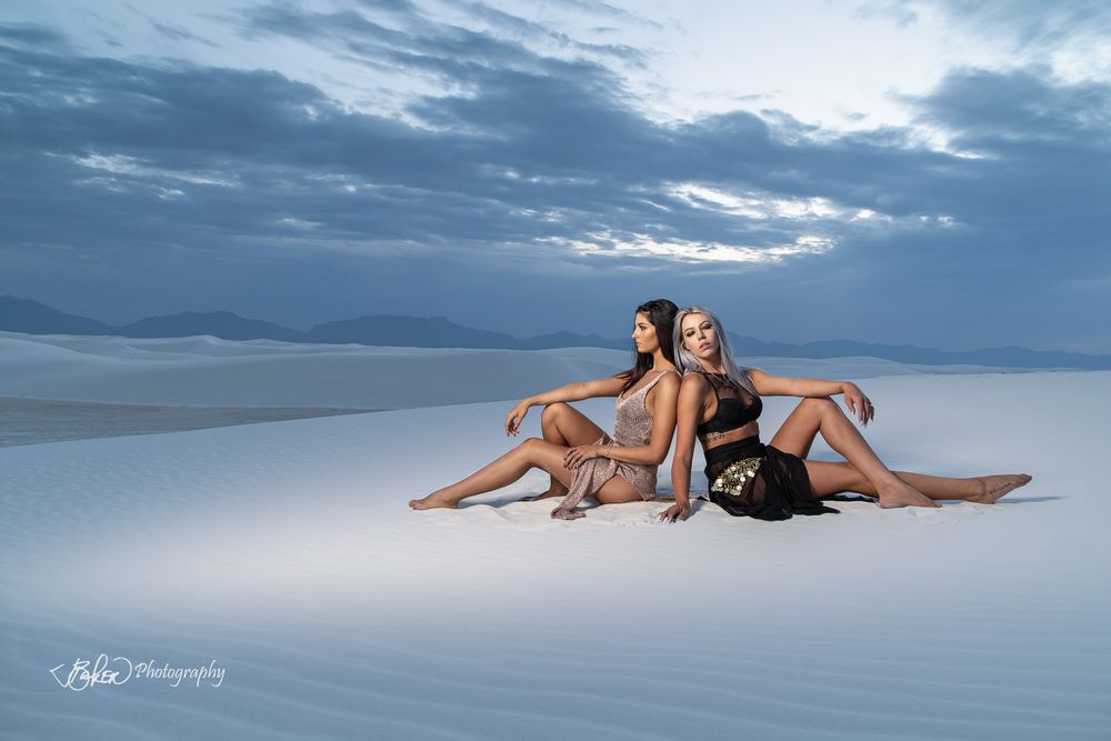 Models pose on the beach at sunset creating artistic silhouettes against the dramatic cloudy sky.