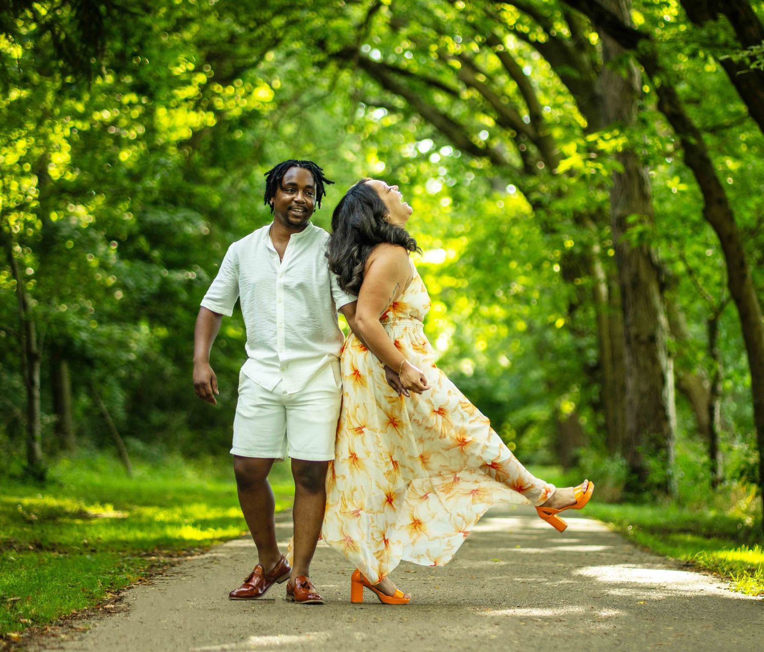A couple walks hand in hand along a lush green forest path during a romantic outdoor photo session.