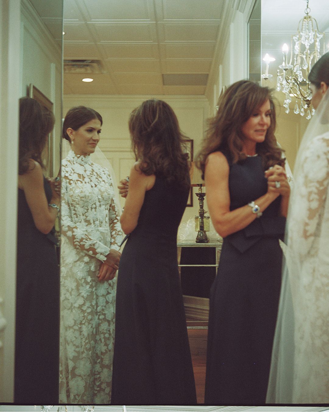 A series of people in black dresses and formal wear stand in a line at what appears to be a wedding or formal event.