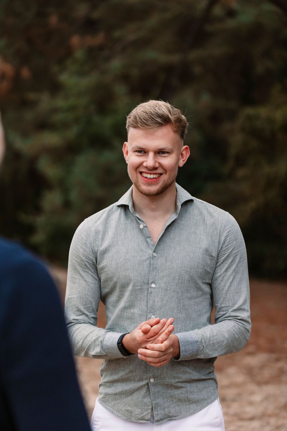 Person in grey button-up shirt smiles warmly during animated outdoor discussion.