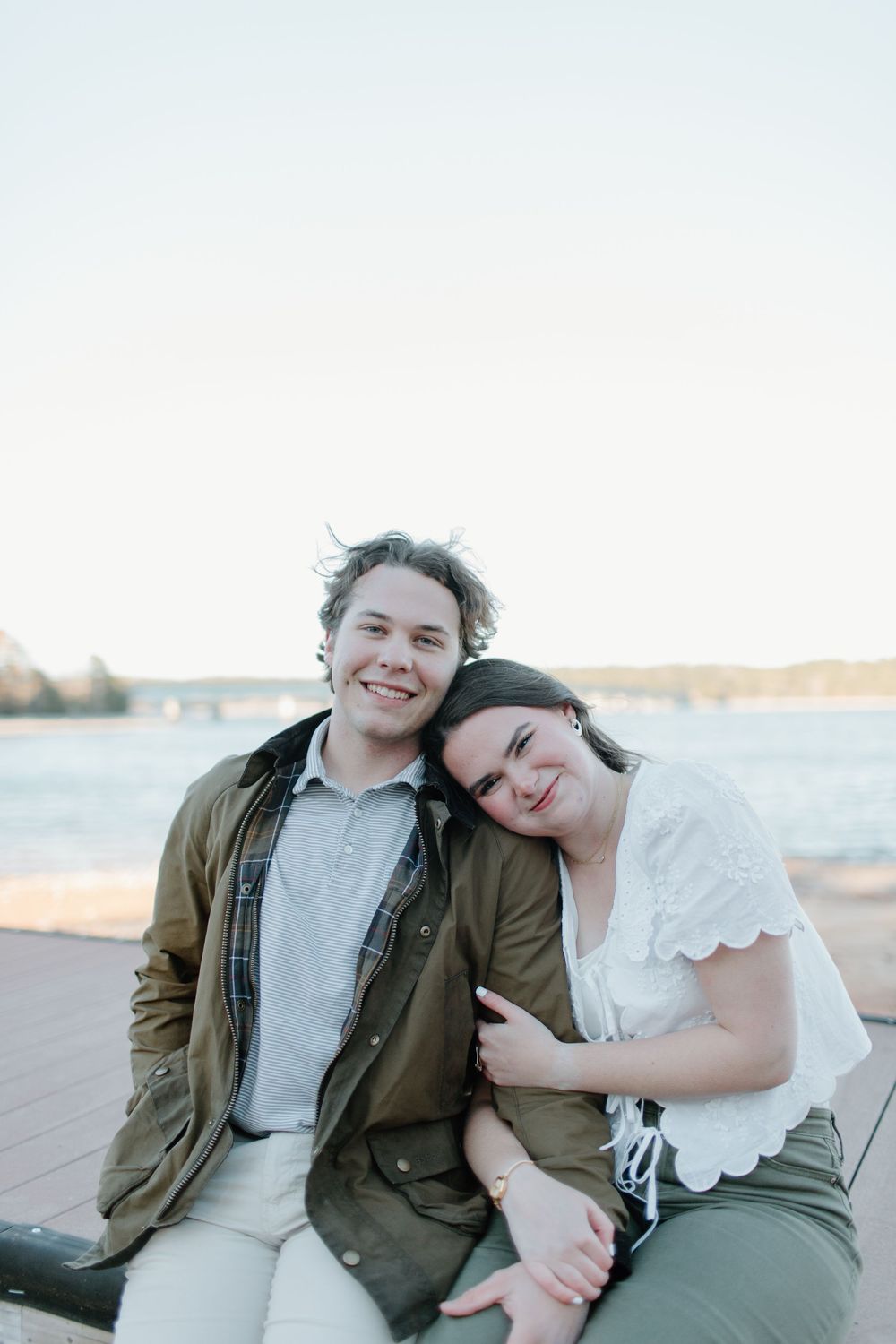 Casual beach engagement photos with couple in relaxed attire by the water.