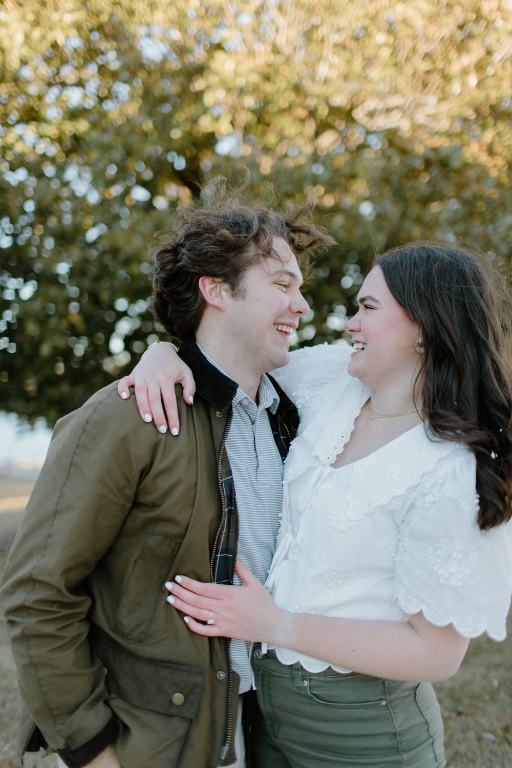 Romantic outdoor engagement photos with couple in green and white casual wear.