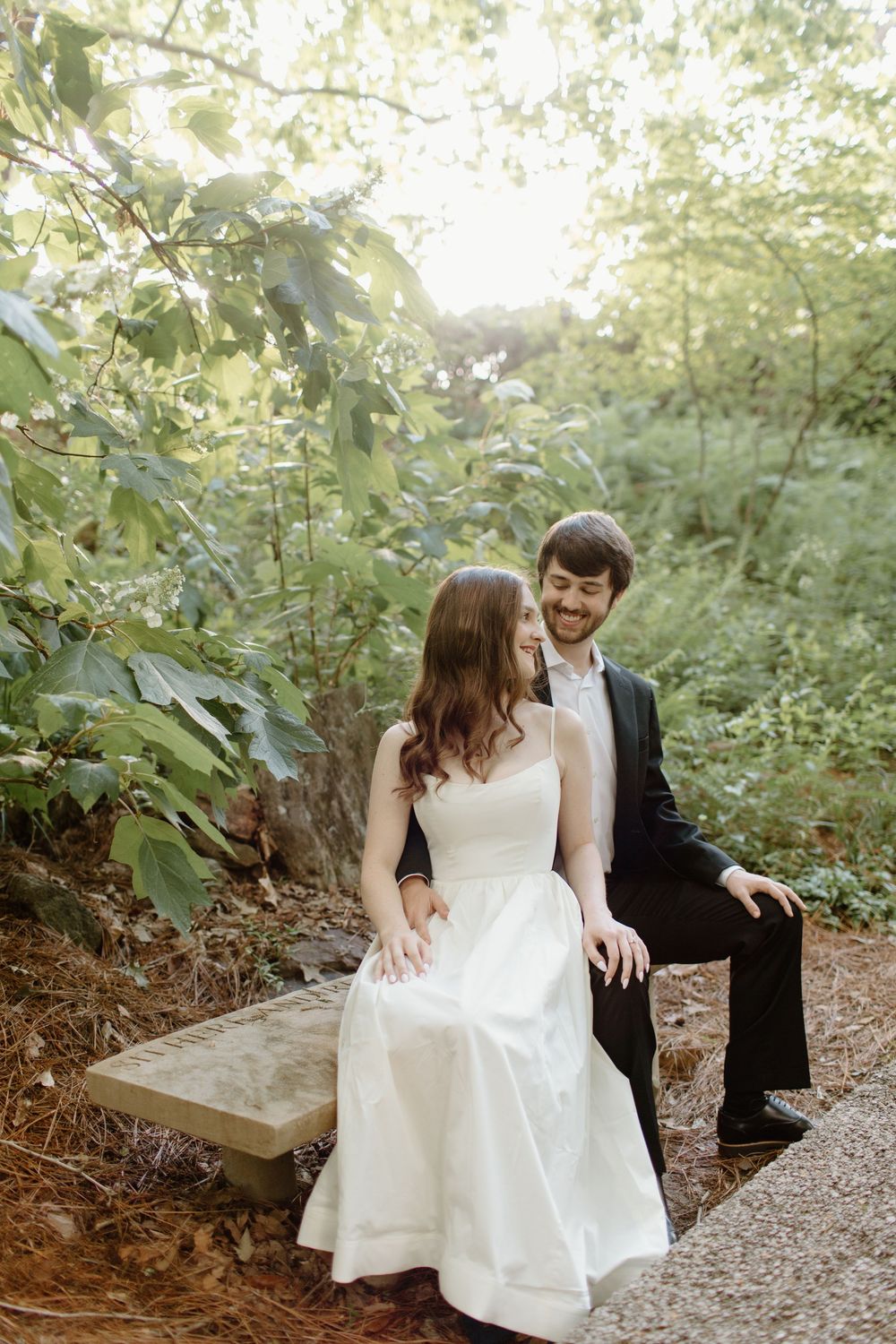 Couple in formal attire sharing romantic moments on garden pathway.