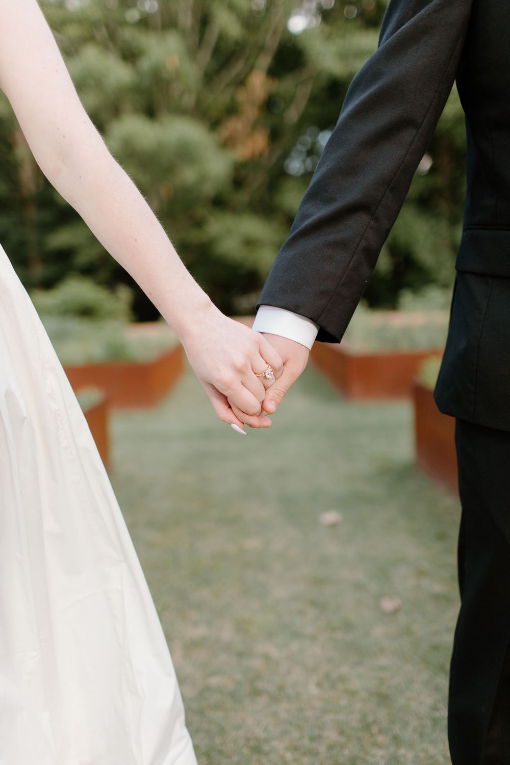 Close-up of couple holding hands while walking outdoors.