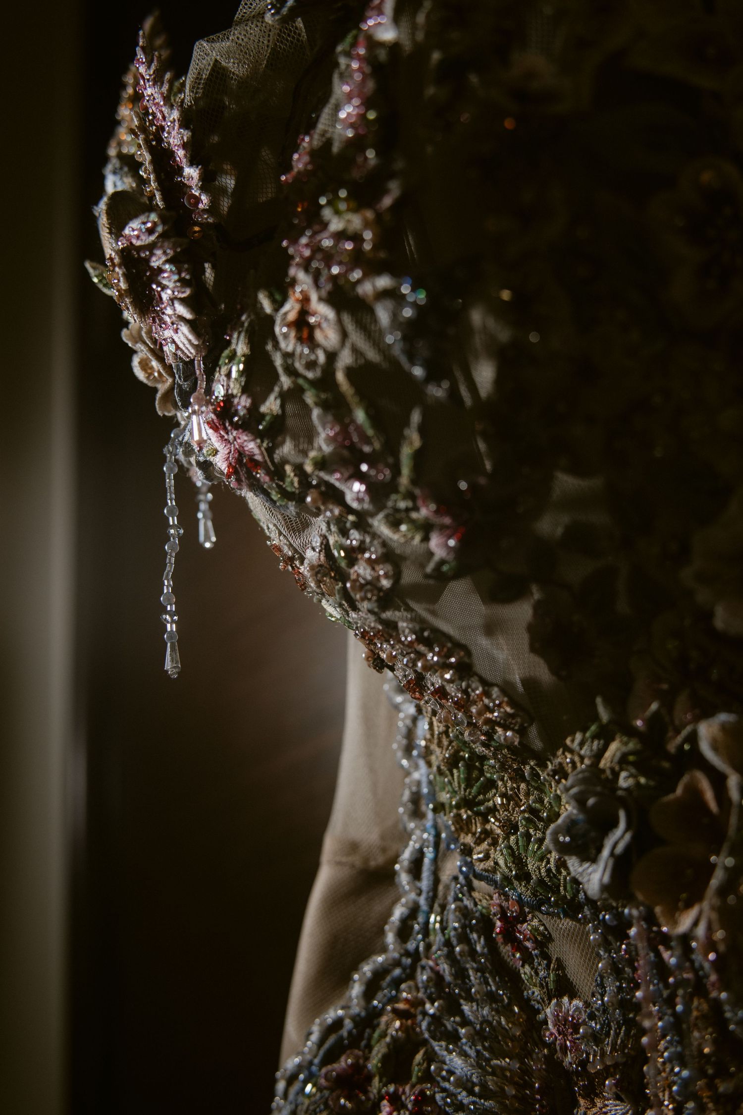 Intricate detail of heavily embellished wedding gown with floral beading, crystals, and gemstone embroidery.