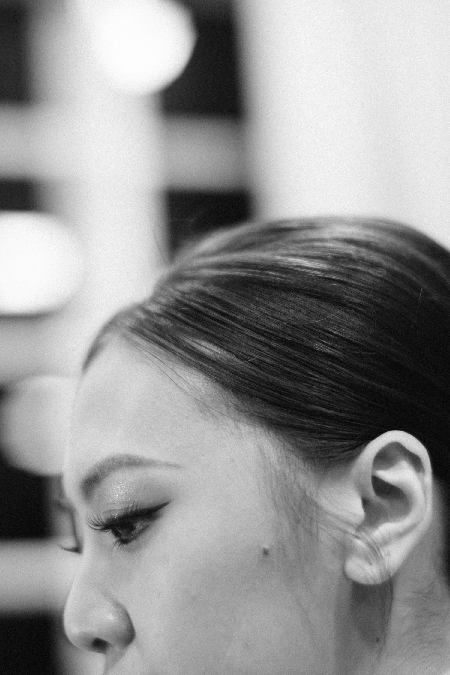 Close-up black and white portrait of bride with sleek updo hairstyle and dramatic eye makeup.