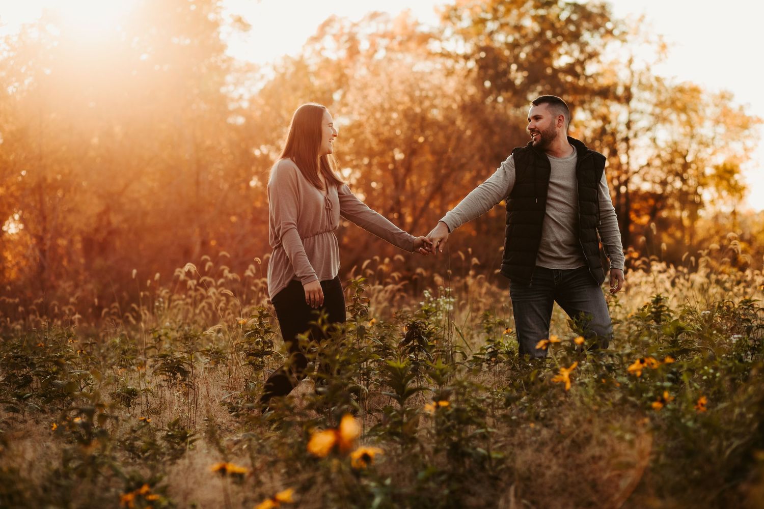 Family walking together through a golden wildflower field at sunset creating silhouettes against the warm sky.