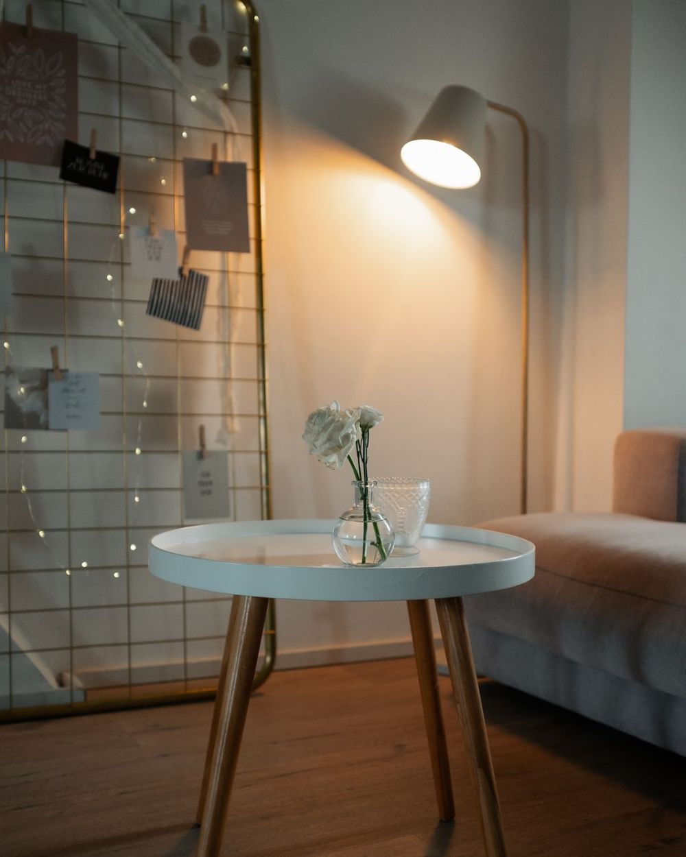 A series of modern white pendant lamps with wooden legs arranged in a row along a hardwood floor interior space.