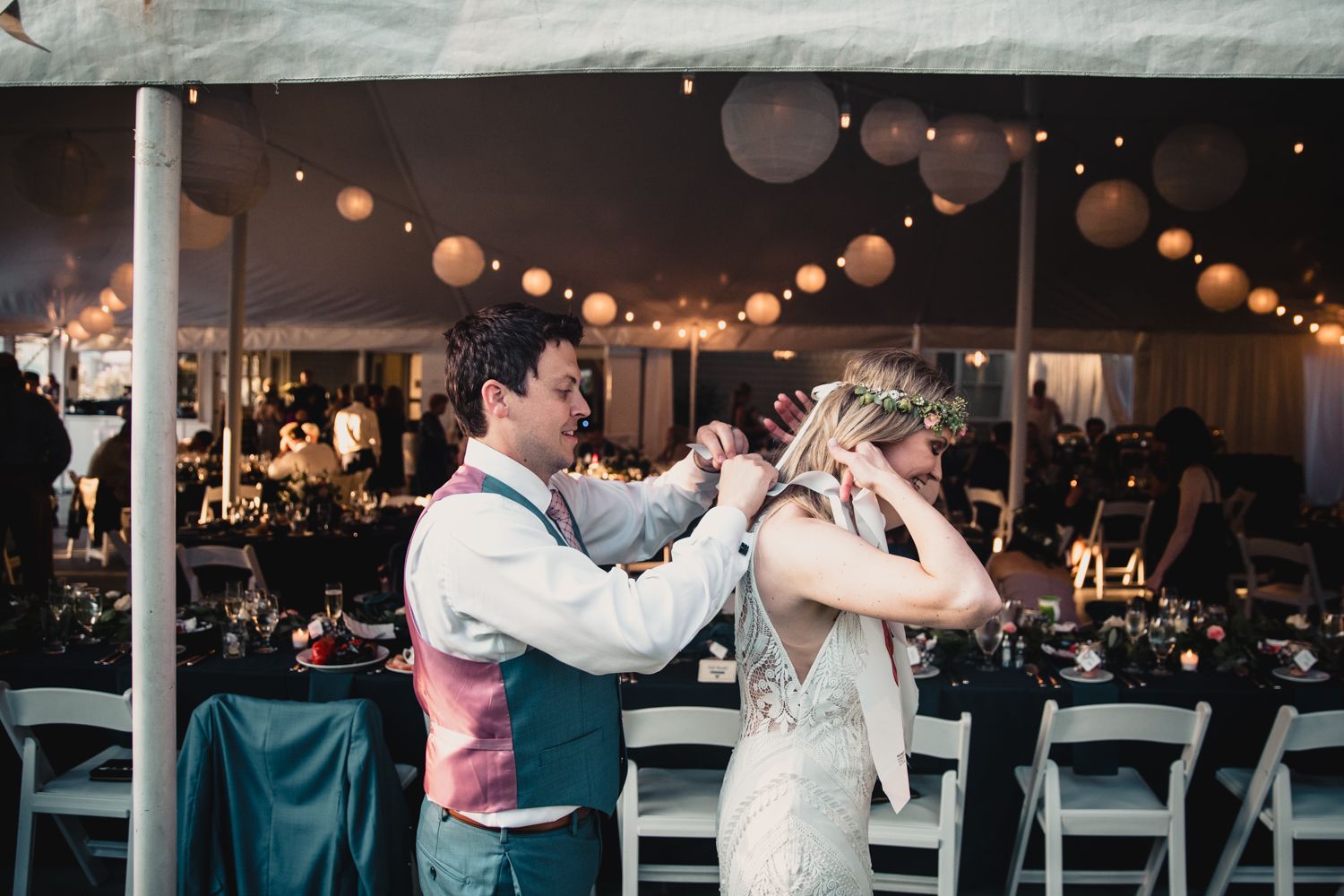 Bride and groom share first dance under romantic tent with string lights and paper lanterns at elegant wedding reception.