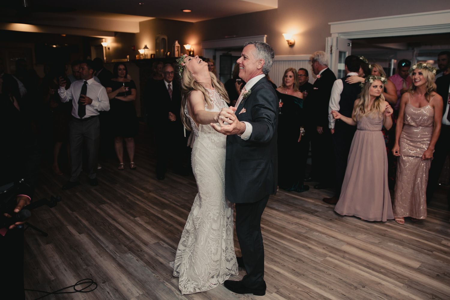 Bride and groom share first dance at elegant wedding reception while guests watch in background.