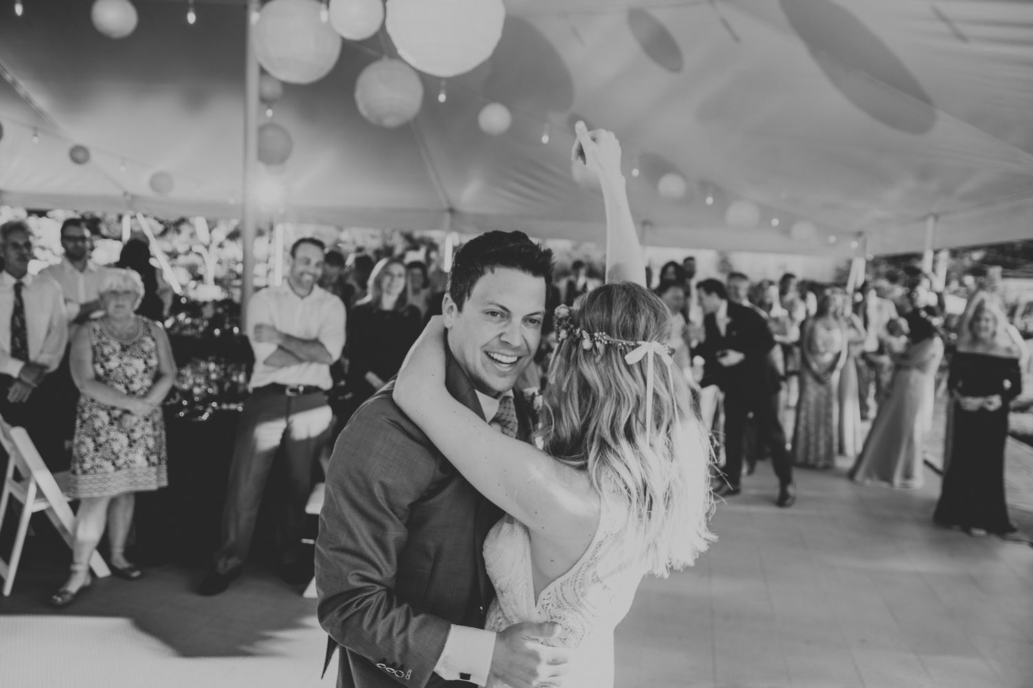 Couple sharing a romantic first dance under paper lantern lights at their elegant wedding reception.