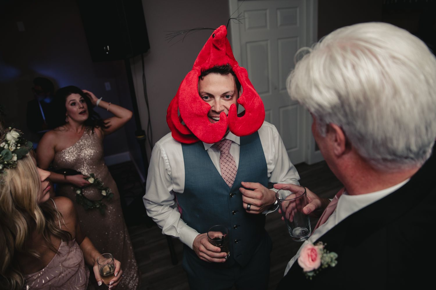 Man wearing red lobster hat entertains guests on wedding reception dance floor.