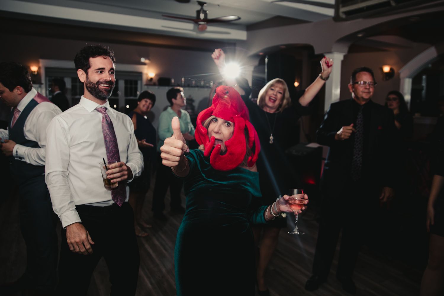 Guests dancing and celebrating at a lively wedding reception, one wearing a fun red costume.
