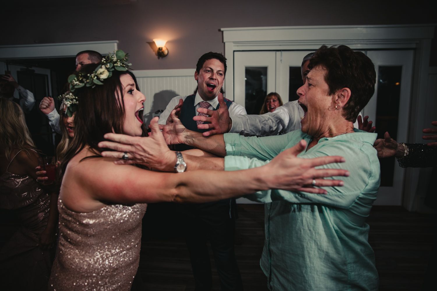 Excited wedding guests dancing and laughing together on the dance floor at a reception.