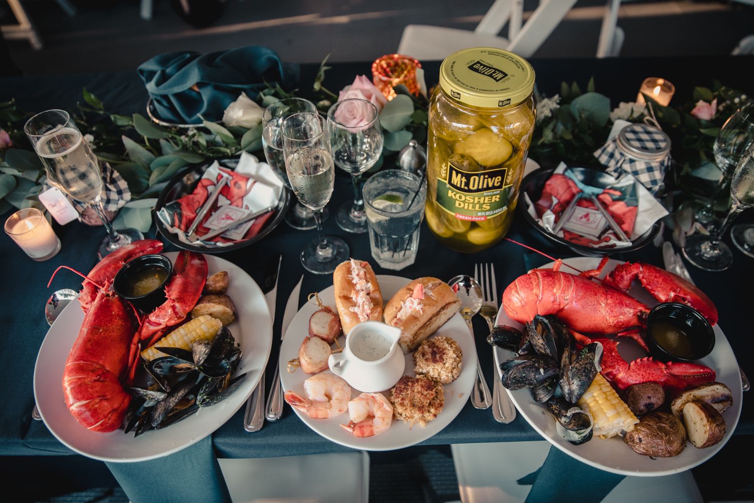 Elegant seafood wedding reception table with lobster, mussels, shrimp, and pickle jar centerpiece.