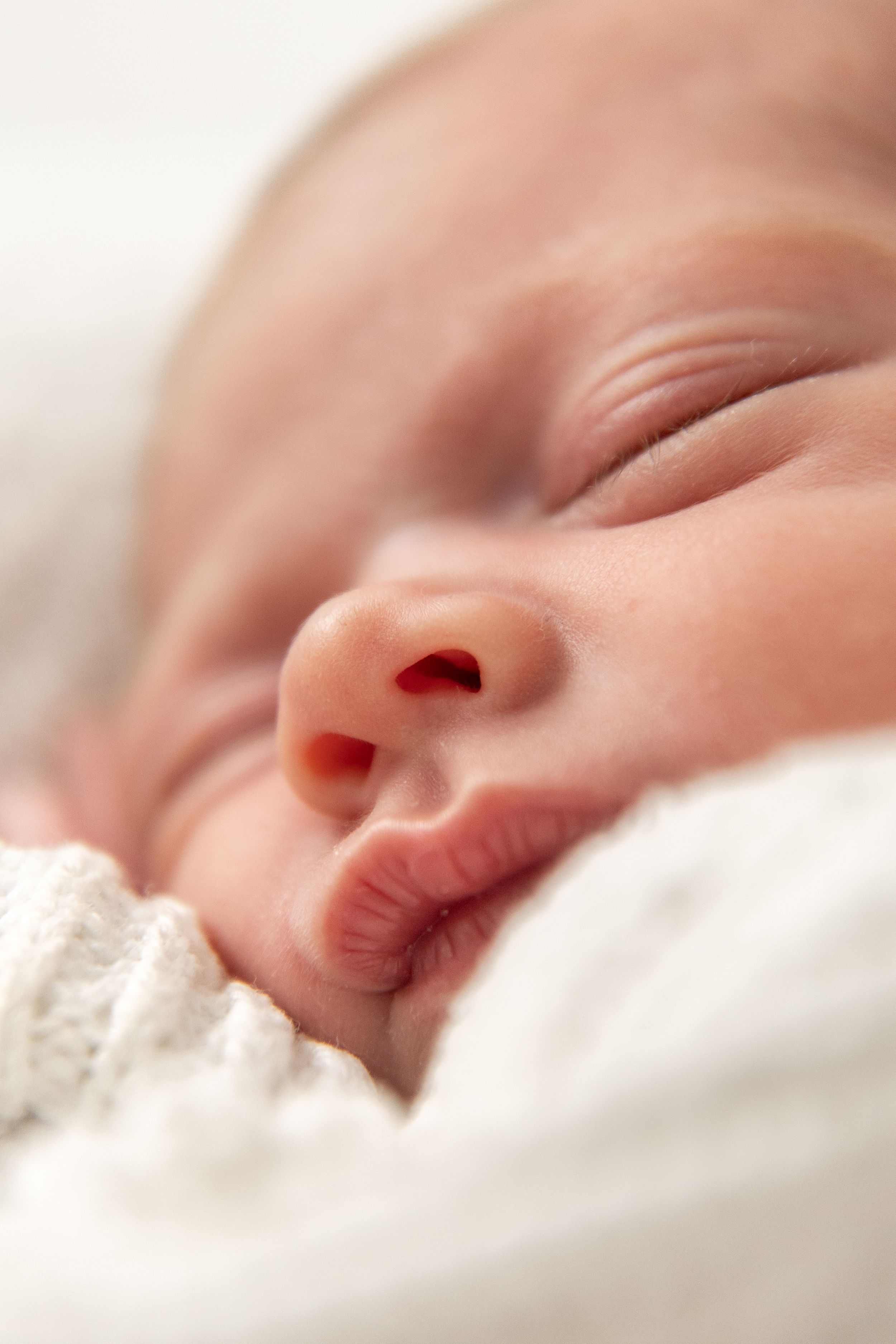 Close-up of a sleeping newborn baby wrapped in a soft white blanket, Nottingham newborn photographer