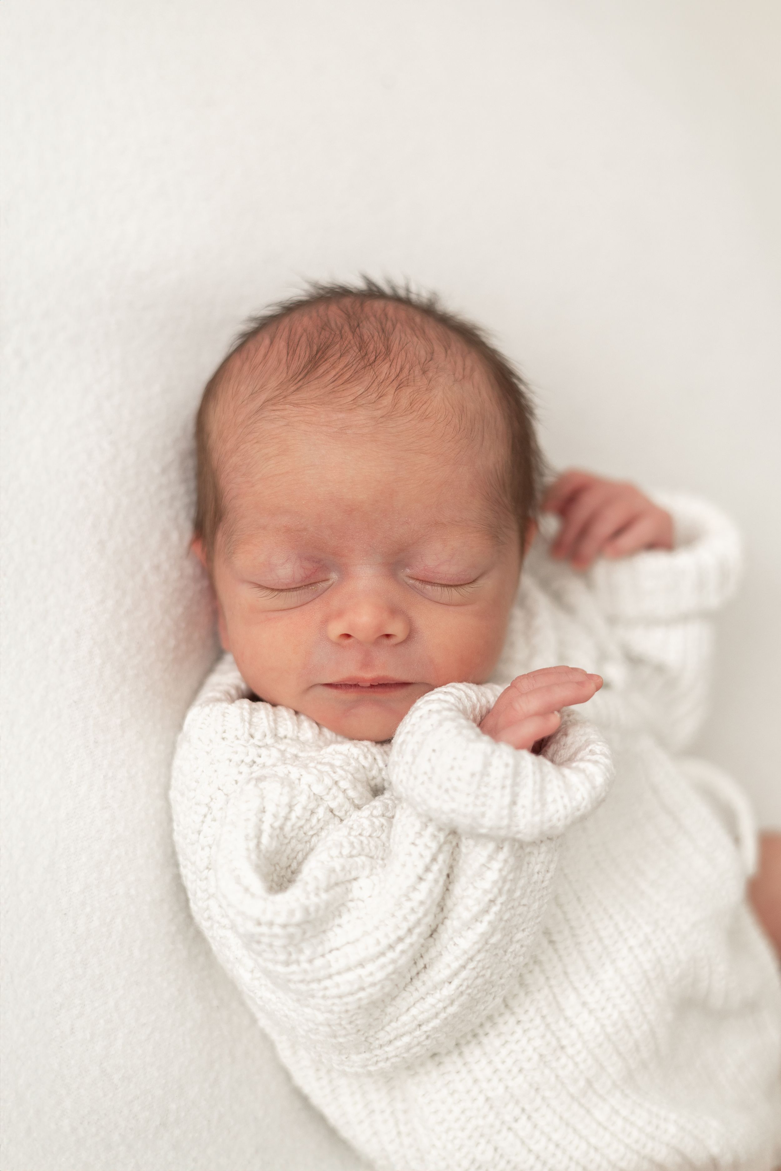 Natural newborn photography Nottingham Peaceful newborn baby sleeping wrapped in a soft white knit blanket